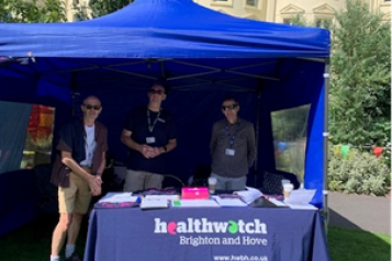Healthwatch team standing under gazebo at festival.