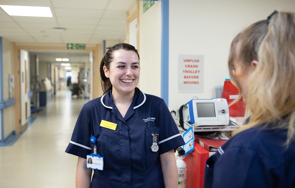 Two medical professionals talking in a corridor in a hospital setting.