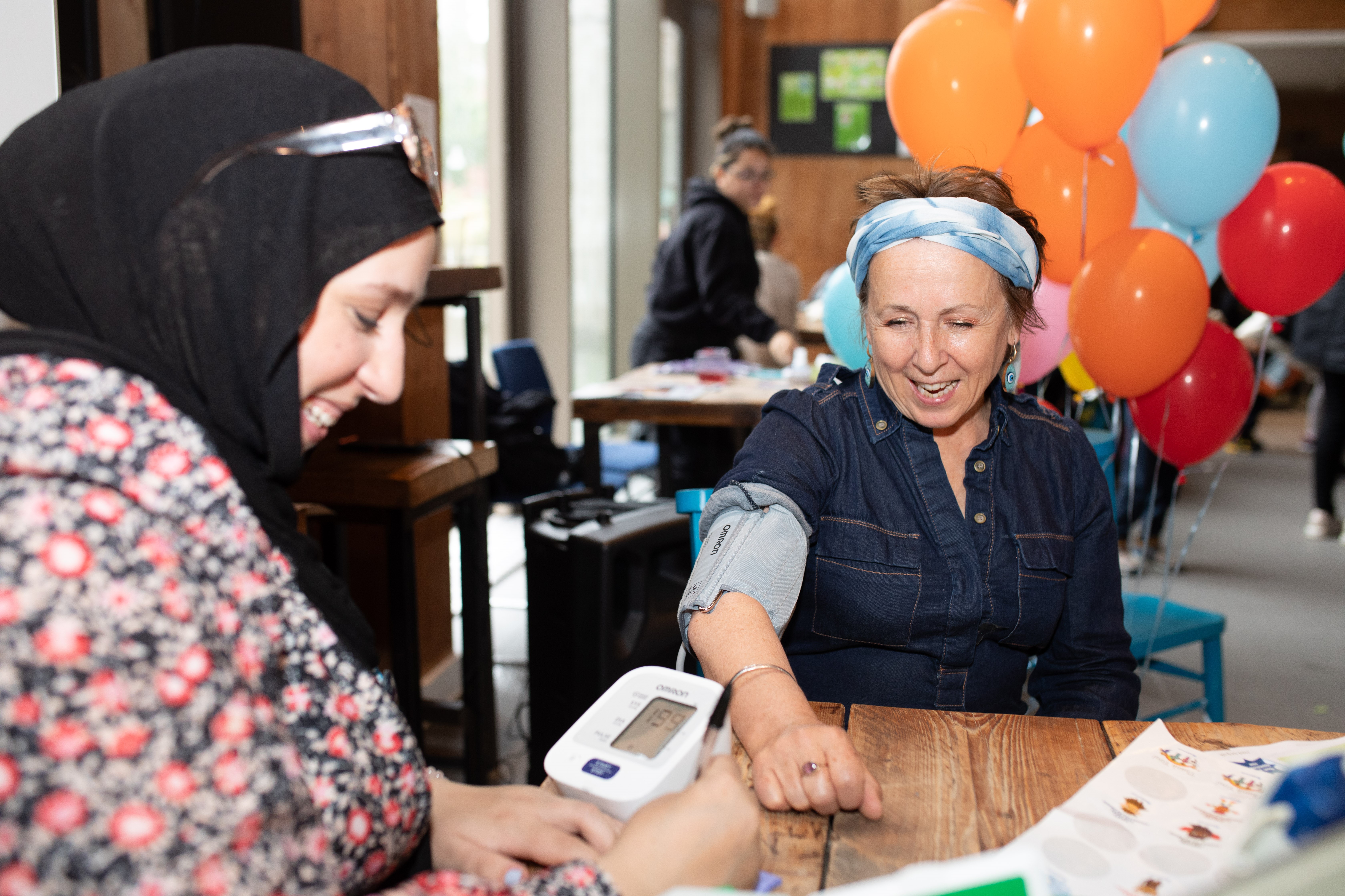 Woman taking another woman's blood pressure.