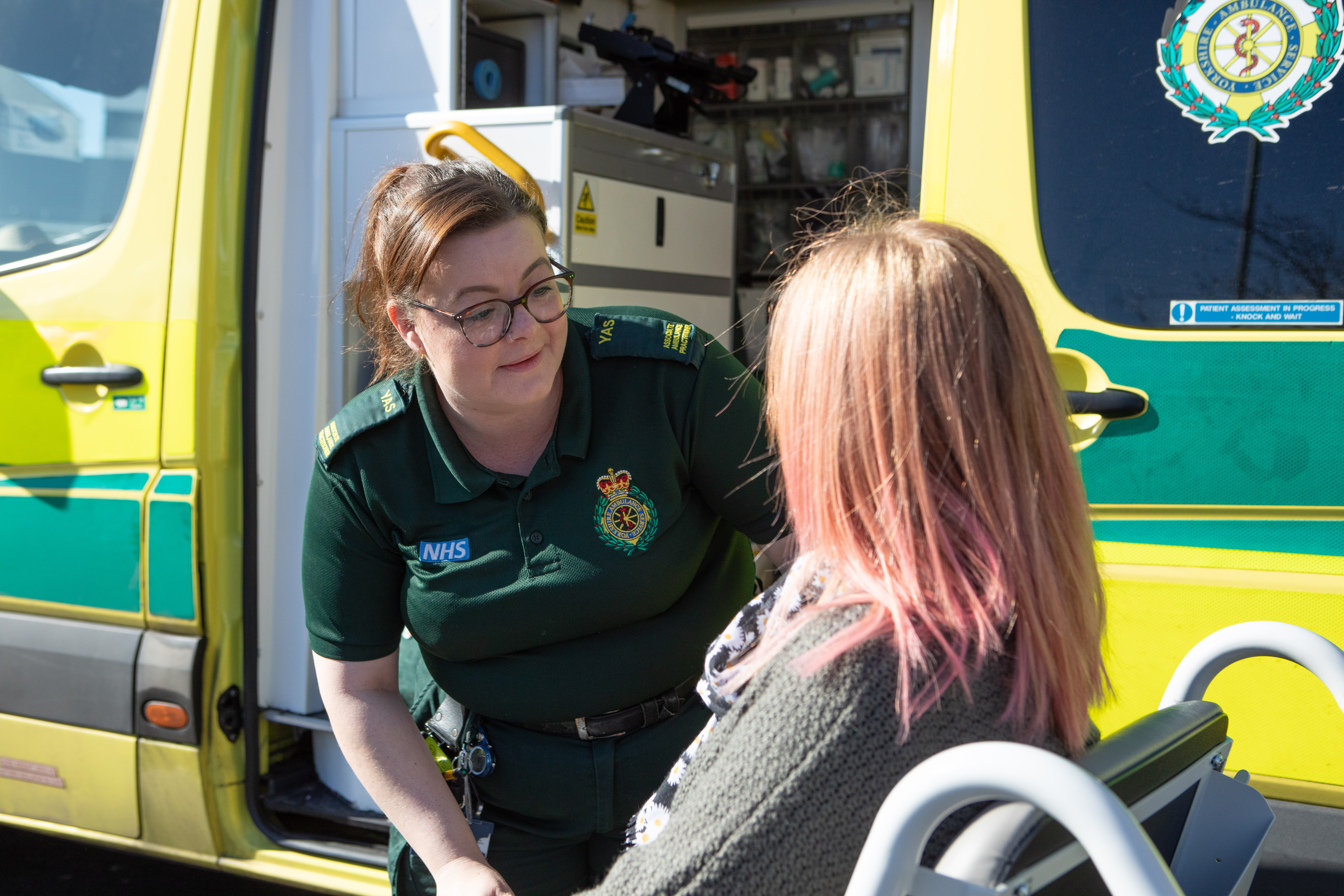 Ambulance worker supporting service user in front of an ambulance. 