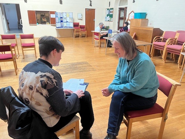 Two women speaking while sitting down.