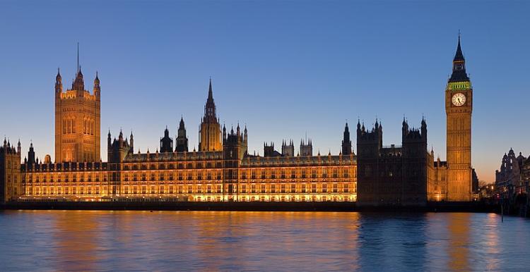 Palace of Westminster lit up brightly as the sun sets, from across the Thames.