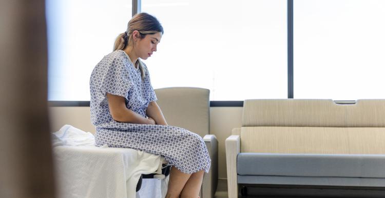 Female patient sitting on hospital bed.