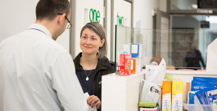 A woman serving a man over the counter in a pharmacy. 