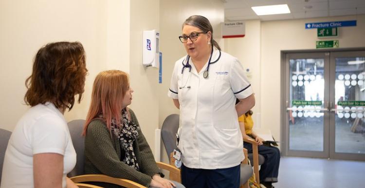 A clinician talking to two people in a waiting area