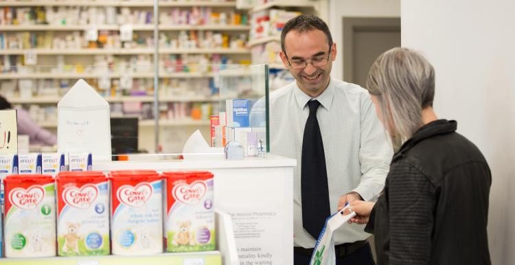 A pharmacist assisting a person in a pharmacy.