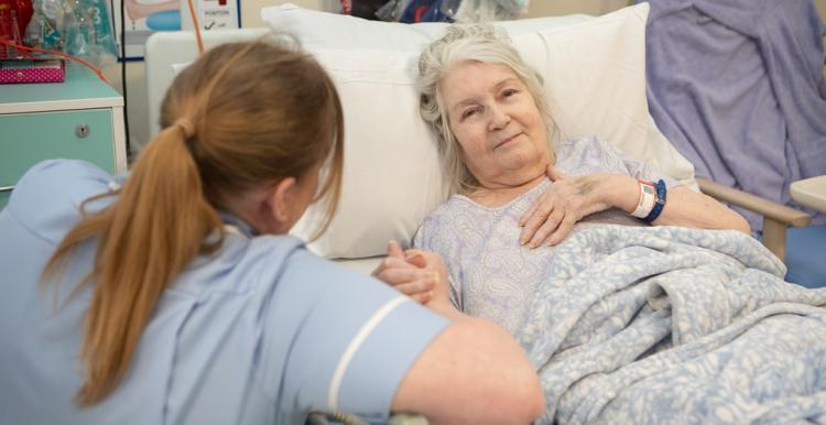 Woman in hospital receiving care at their bedside.