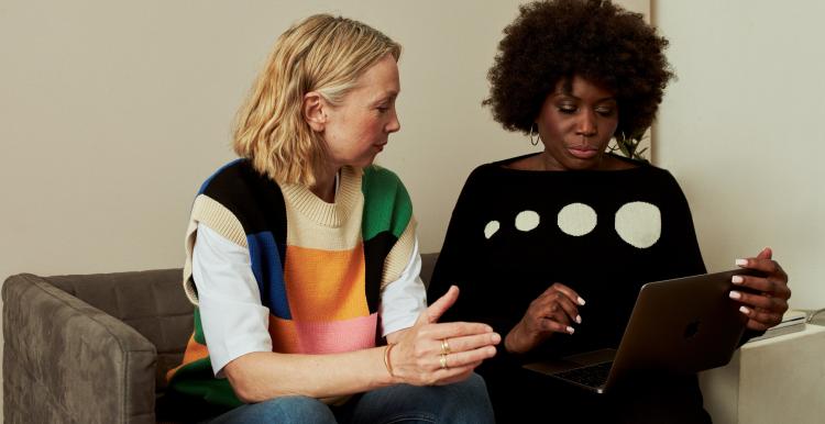 Two women on sofa looking at a laptop together