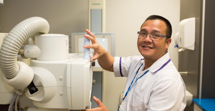 A medical professional using medical equipment and smiling.