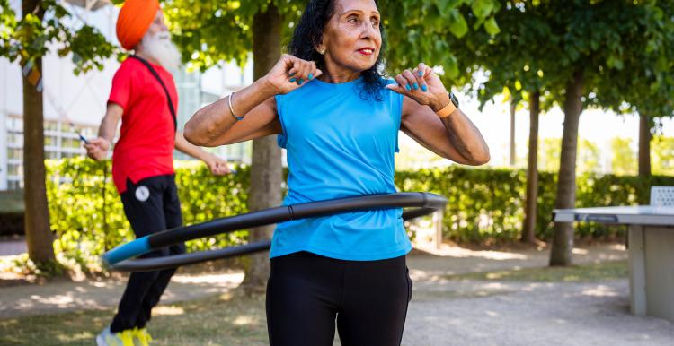 Two people exercising outside with a skipping rope and hula hoop