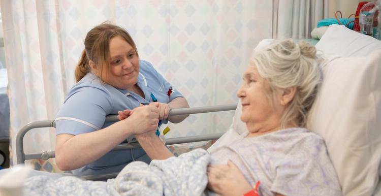 Medical professional holding the hand of a patient in a hospital setting.