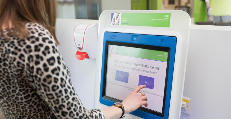 A person using a screen to check in for an appointment in a clinical setting.