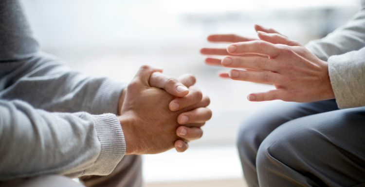 Close up of hands of two people, suggesting a conversation.