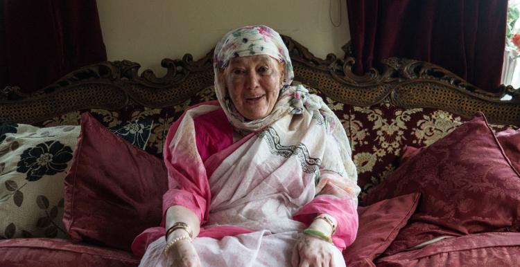 Older woman smiling on a sofa.