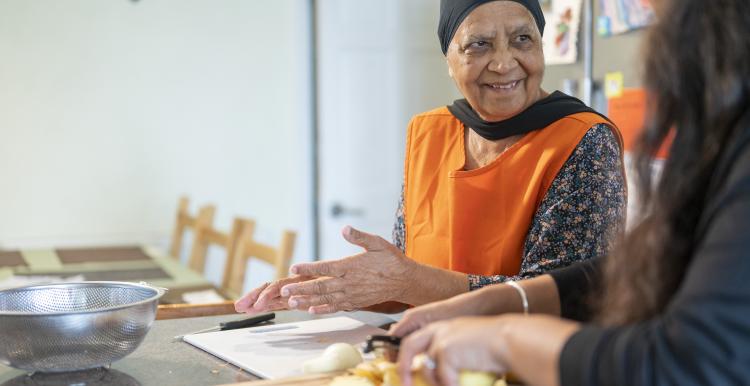 An older woman and another person preparing food together.