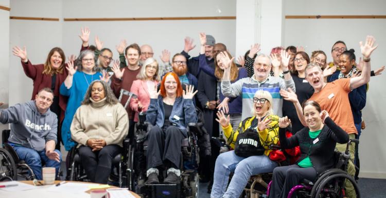 A group photo of a professional team in a conference room with everyone smiling and putting their arms up.