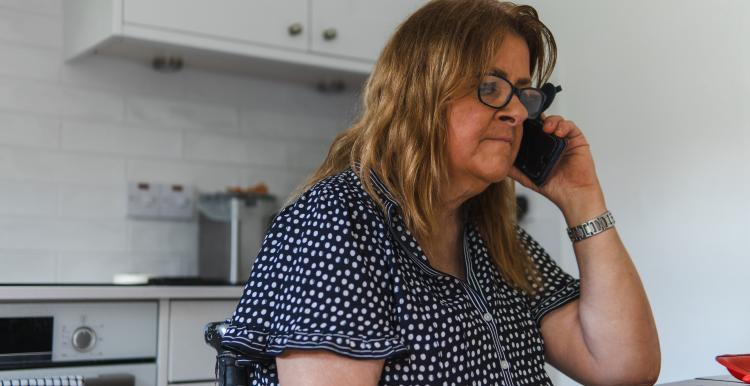 Woman using a phone in a kitchen.
