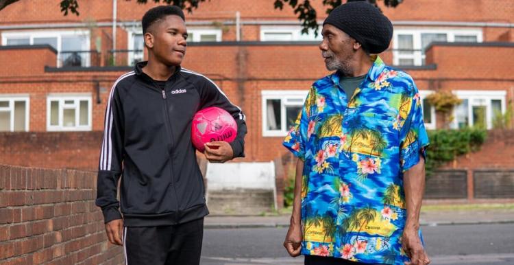Man and boy with a football walking down the street