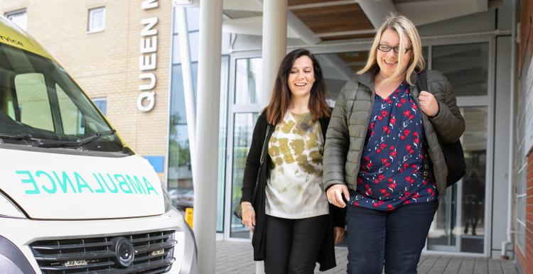 Two women walking past an ambulance.