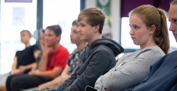 Children sat in chairs in a line.