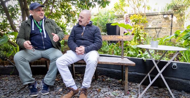 Two men chatting sat outside.
