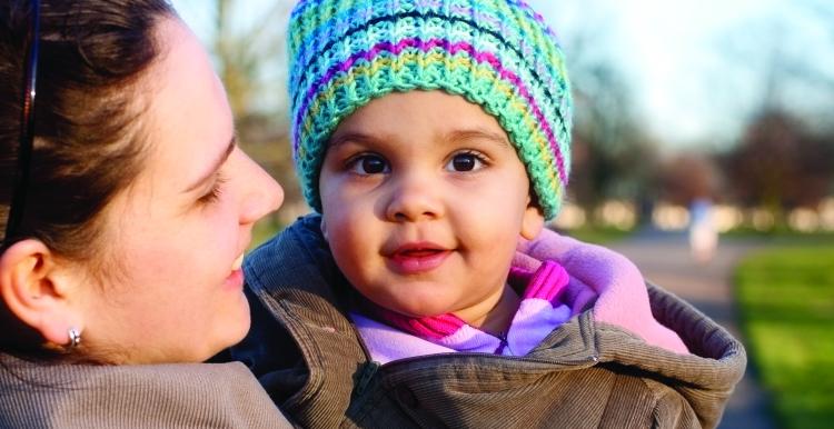 A baby being held by an adult in a park setting.