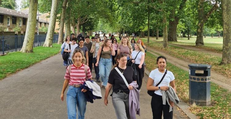 A group of people walking along a park avenue together.