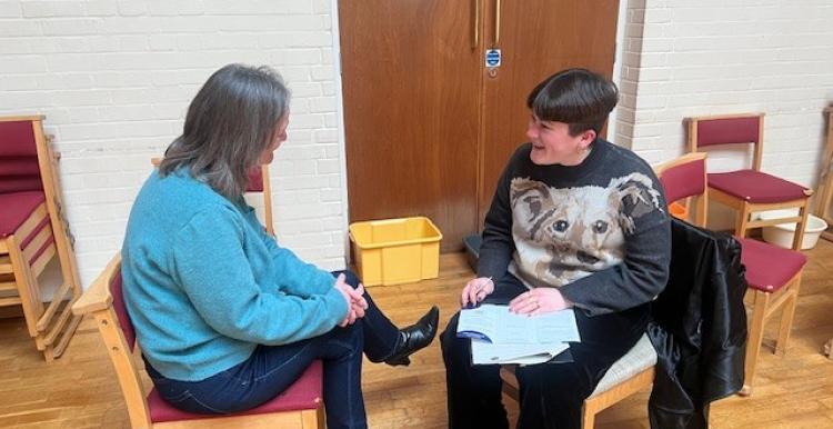 Two women talking while sat down.