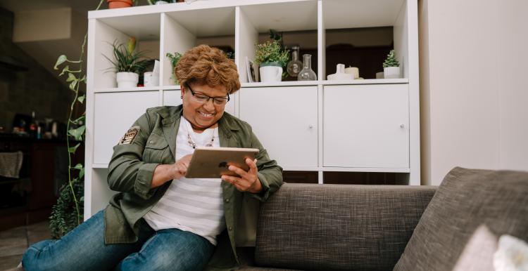 Woman using an iPad on a sofa indoors.
