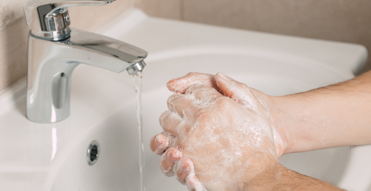 Hands being washed in a sink.