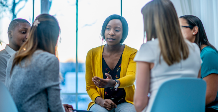 A group discussion with several people sat in chairs indoors. 