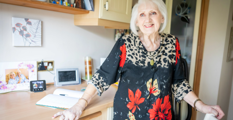 An older woman in a kitchen smiling.