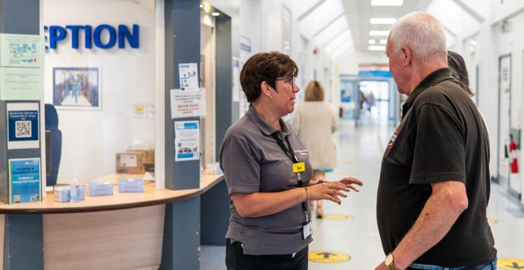A volunteer talking to a man in a hospital corridor.