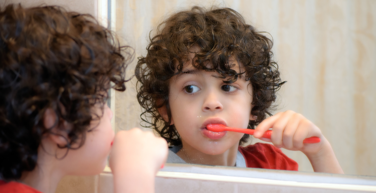 Child looking in mirror while brushing their teeth.