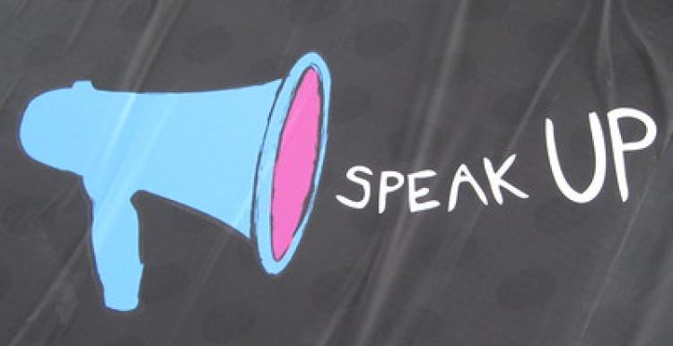 Blue microphone to the left hand side, Speak Up in white writing centrally aligned