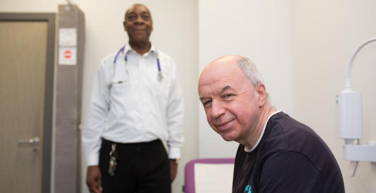 GP Surgery, Man in focus, in foreground to right, Doctor blurred, in background to left