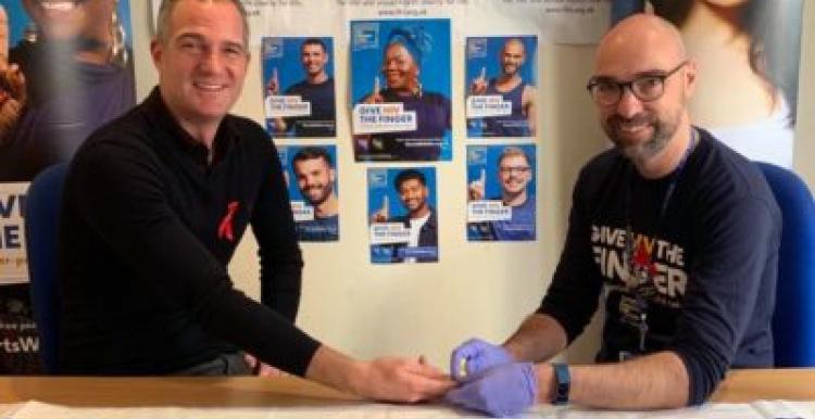 Photogrpah of Hove MP Peter Kyle, HIV Testing, Terrence Higgins Trust Posters IN foreground and Background