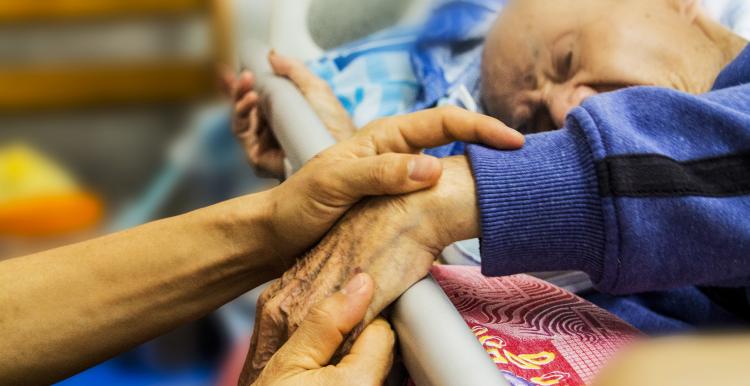 Elderly man in hospital bed, close up of hand being held
