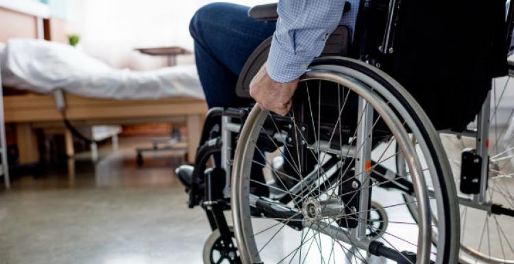 man in wheelchair by bed