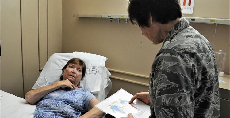 Female patient in hospital bed, doctor facing patient with clipboard