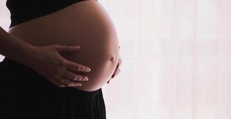 pregnany woamn, focused on stomach, standing right side of shot