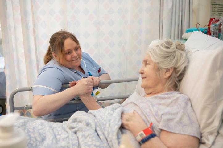 Medical professional holding the hand of a patient in a hospital setting.