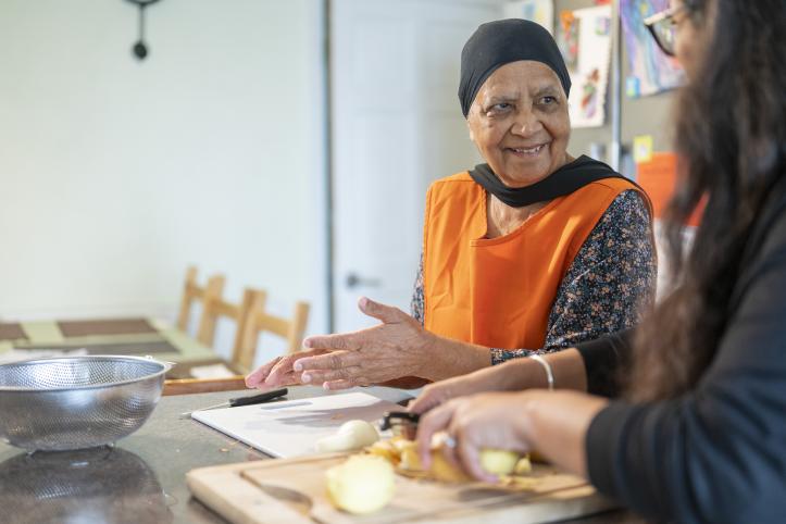 An older woman and another person preparing food together.