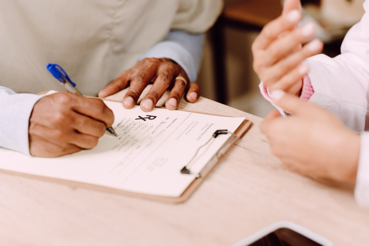 Someone filling out a form next to another person. This is a close-up shot of two sets of hands.