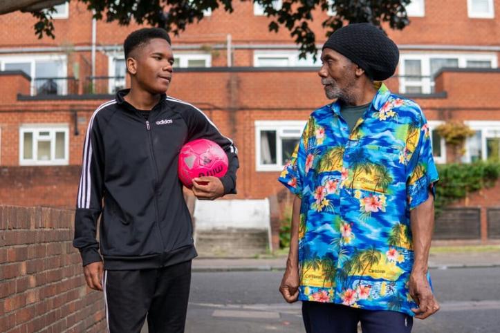 Man and boy with a football walking down the street