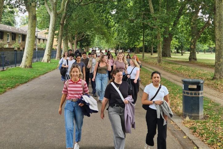 A group of people walking along a park avenue together.