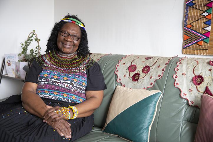 Woman sat smiling on sofa indoors.