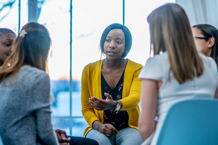 A group discussion with several people sat in chairs indoors. 