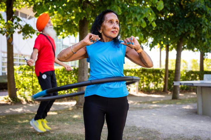 Two people exercising outside with a skipping rope and hoola hoop
