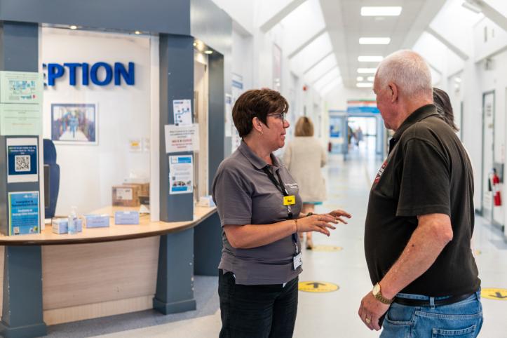 A volunteer talking to a man in a hospital corridor.